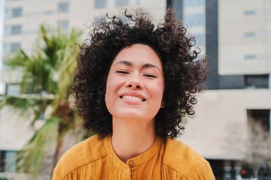 Front view of happy young hispanic woman smiling with curly hair Close up portrait of cracy lady laughing and having fun. High quality photo