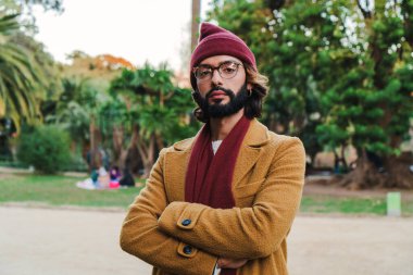 Front view of caucasian man with crossed arms and goggles looking serious at camera. Mid adult male with beanie hat standing outdoors with pensive attitude. High quality photo