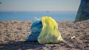 Throwing a lot of garbage bags, trash, waste, rubbish on the sand of the beach littering the nature. Environmental concept. Slow motion. High quality 4k footage