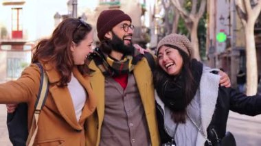 Üç mutlu çok ırklı turist arkadaş grubu hafta sonu gezisinde birlikte eğleniyorlar. Dışarıda yürüyen ve gülümseyen genç insanlar birbirlerine sarılıyorlar. Tatil konsepti. Ağır çekim. Yüksek kalite 4k
