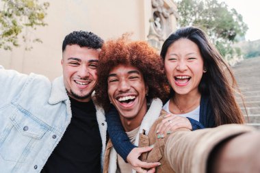 Bir grup mutlu genç arkadaşın gülüp selfie çekerken eğlendikleri portreyi yakından çek. Genç çok ırklı insanlar dışarıda kameraya bakıp gülümsüyor. Arkadaşlık kavramı