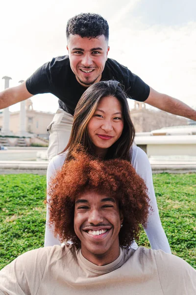 カメラを見て楽しさと笑顔を持つ3人の多人種の若い友人のグループの垂直方向のビュー 明るい態度で幸せな多民族の人々のフロントビュー ライフスタイルのコンセプト 高品質 — ストック写真