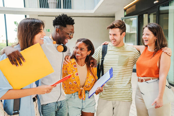 Group of multiracial students talking and smiling after class at university campus. Diverse tenagers laughing and having fun at the breack of the high school. Education concept. High quality photo