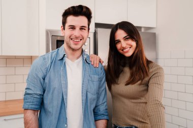 Genç, beyaz bir çift kameraya bakıp evde dinleniyor. Yeni evlerinde duran mutlu evliliğin ön görüntüsü. Sevecen koca ve güzel eşin gülüşünün portresi.