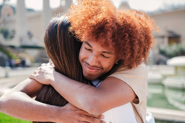 Genç mutlu çiftin birbirine sarılma portresi. Afro saçlı, gülümseyen ve kız arkadaşına sevgi ve sevgi gösteren Afro-Amerikalı bir genç.