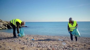 Bir grup ekoloji gönüllüsü kumsalı geri dönüştürmek için kum atıkları topluyor. Birkaç çevreci eylemci, dünyayı ve denizi kurtarmak için poşetlerle plastik topluyor. İnsanlar gezegeni temizliyor.
