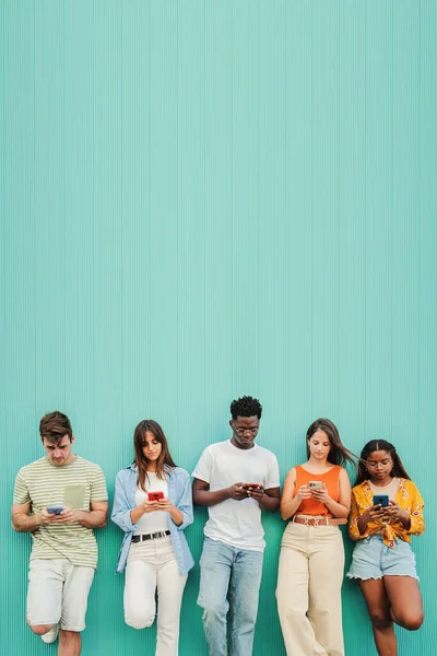 Vertikalt Grupp Multietniska Tonåringar Beroende Att Använda Smartphone Blå Bakgrund — Stockfoto