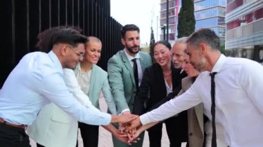 Ağır çekim. Bir grup iş adamı iyi bir anlaşmayı kutlamak için el ele tutuşur. Şirket ekibi işbirliği ve destek yapıyor. Ortaklık toplantısında gülümseyen çalışanlar ya da iş arkadaşları. Yüksek