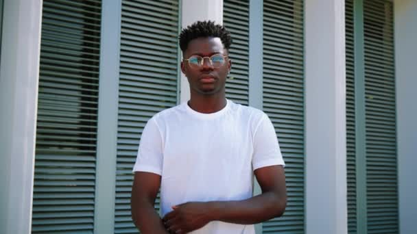 年轻的非洲裔美国人的画像 严肃而自信的人站在外面看着相机 双臂交叉 大学校园里英俊的大学生摆出一副心平气和的样子 — 图库视频影像
