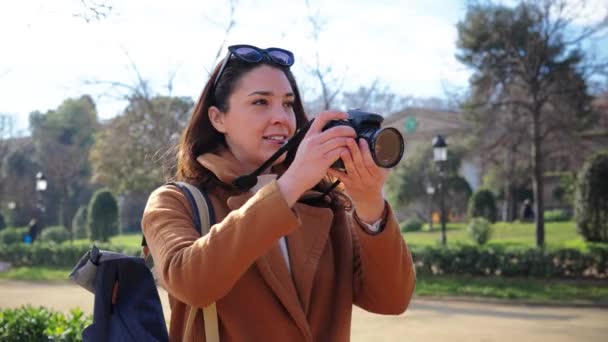年轻的女摄影师在周末的旅行活动中微笑着拍了一张艺术照 一个高加索的嬉皮士女人在度假旅行中喜欢用复古专业相机拍照 — 图库视频影像