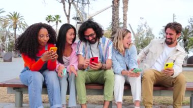 Akıllı telefonu internette gezinmek, selfie çekmek, sosyal medyayı paylaşmak ve sipariş vermek için kullanan bir grup genç arkadaş. Beş mutlu çok ırklı insan gülümsüyor ve cep telefonuyla eğleniyor.