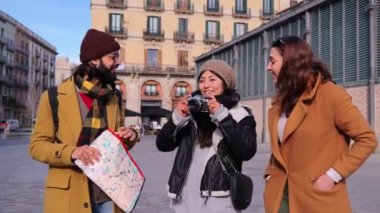 Bir grup mutlu turist arkadaş. Fotoğrafçı gülümsüyor ve Barcelona caddesinde fotoğraf çekiyor. Kamerayla odaklanan genç gezginler Avrupa 'da bir yolculukta bir anıt. İnsanlar etrafı geziyor.