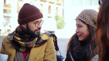 Bir grup genç, kahve dükkanının terasında oturmuş birlikte gülüp eğleniyorlar. Üç arkadaş bir fincanda içiyor ve bir restoranda arkadaşça sohbet ediyor.