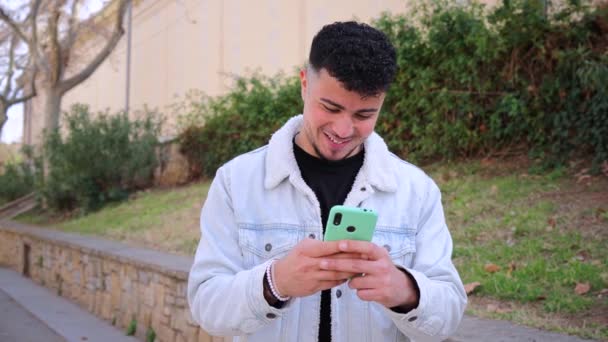 Chico Marroquí Sonriente Divirtiéndose Usando Teléfono Inteligente Para Jugar Videojuego — Vídeos de Stock