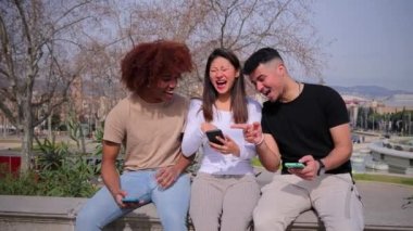 Genç çok kültürlü gençler akıllı bir telefondan komik görüntüler izliyorlar. İnternette cep telefonu uygulaması ile gezinen gülümseyen üç yetişkin insan. Cep telefonu kullanarak video oyunu oynayan hippi öğrenciler