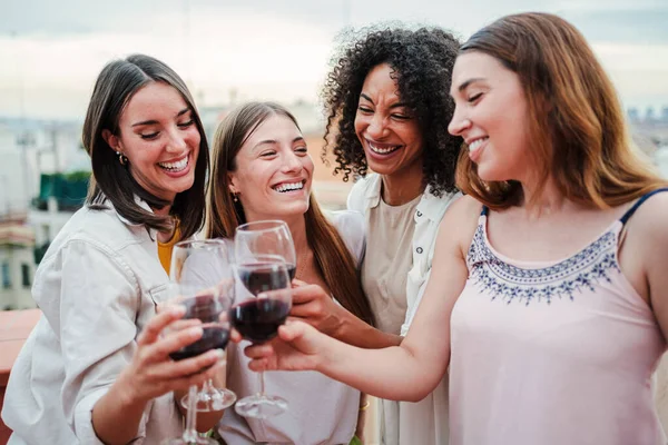 Bir grup mutlu genç bayan arkadaş çatı katındaki bir partide kadeh kaldırırken, içerken ve gülerken eğleniyorlar. Dört neşeli kız bardaki sosyal bir buluşmada içkiyle şıngırdıyor.