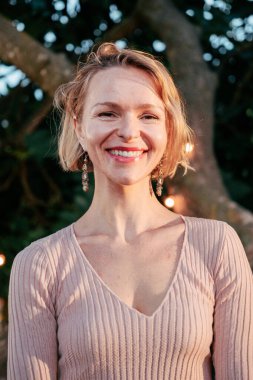 Orta yaşlı bir kadının dikey portresi kameraya dostça bakıyor. Gururlu ve pozitif tavırlı, mutlu, olgun bir beyaz kadın. Gülümseyen orta yaşlı kadın.