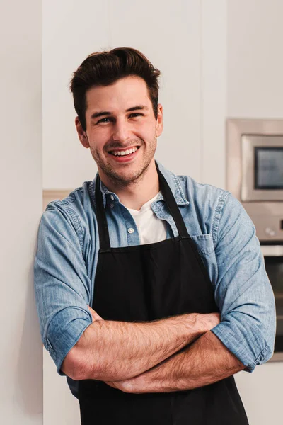 Pionowy Portret Przystojnego Białego Mężczyzny Fartuchu Stojącego Kuchni Uśmiechającego Się — Zdjęcie stockowe