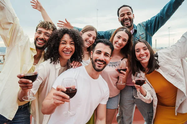 Bir grup yetişkin arkadaş çatıdaki mezunlar toplantısında ya da doğum günü partisinde içki içerek kadeh kaldırırken eğleniyorlar. Mutlu insanlar birlikte kutlama yaparak eğleniyorlar. Yüksek