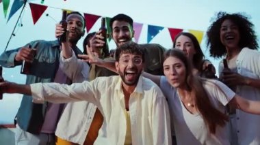 Büyük bir grup mutlu genç arkadaşın portresi gülümseyen ve eğlenen çatı katı partileri, sosyal toplantılar ya da gece vakti doğum günü toplantıları, bira içip birlikte eğleniyorlar.