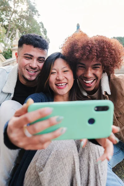 携帯電話でセルフィーを取る楽しみを持っている十代の多人種間の友人のグループの垂直の肖像画 若い幸せな人々 笑顔と面白いビデオを見ているか 携帯電話でビデオ通話を持っている — ストック写真