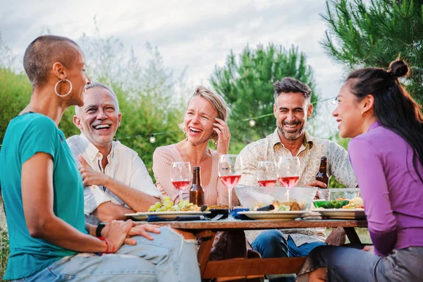 Olgun insanlar öğle yemeği partisinde kırmızı şarap içerek evlerinin arka bahçesinde yemek masasında oturuyorlar. Orta yaşlı kankaların sosyal buluşması, eğlenmek ve komik bir doğum günü buluşmasında konuşmak.