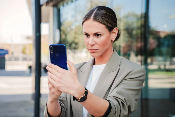 认真的女商人看着她的手机屏幕 读着一条新的信息 遇到了困难和问题 不安的女商人拿着她的智能手机 检查金融市场的应用 — 图库照片
