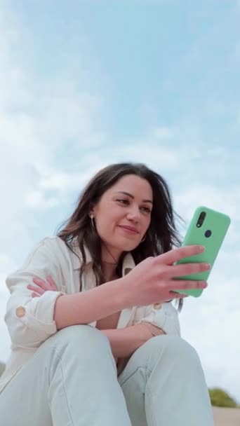 Açık Havada Oturan Bir Cep Telefonu Uygulamasından Içeriği Izleyen Genç — Stok video