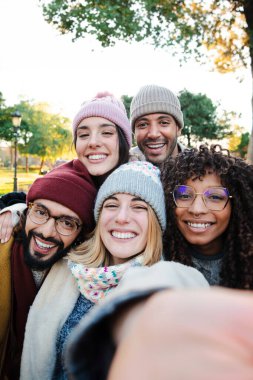 Seyahat gezisinde eğlenen bir grup çok ırklı gencin dikey selfie portresi. Amigo arkadaşların hafta sonu birlikte eğlenirken kameraya bakması ön planda. Yüksek kalite