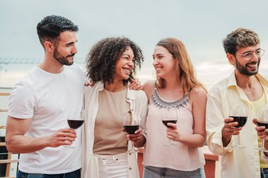 Bir grup genç arkadaş sohbet edip şarap içerek eğleniyor. Yetişkin arkadaşlar parti kutlamalarında gülümsüyor ve şarap kadehleri tutuyorlar. Dairenin çatısında alkol bardaklarıyla gülümseyen erkekler ve kadınlar