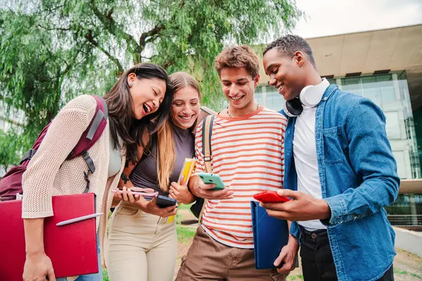 Sosyal medyada cep telefonu uygulaması olan bir grup öğrenci birlikte eğleniyor. Akıllı telefonlarını kullanan mutlu arkadaşlar. Kampüste cep telefonuyla internette gezinen çok ırklı gençler.