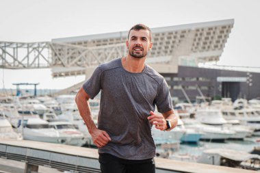 Genç ve güçlü erkek bir maraton, yarış ya da yarış için koşuyor, kardiyo sporundan zevk alarak çaba ve dayanıklılık gösteriyor. Spor yaparken yakışıklı bir adam koşuyor.