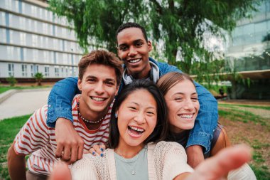 Bir grup genç lise öğrencisi dişlek bir gülümsemeyle dışarıda selfie çektirip gülüyorlar ve birlikte eğleniyorlar. Mutlu gençler fotoğraf çekiyor.