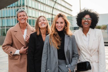 Group of proud businesswomen smiling and looking at camera at workplace. Real executive women staring front, laughing together with suit and successful expression. Corporate female employees meeting clipart