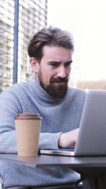 Girişimci serbest meslek adamının dikey portresi dizüstü bilgisayarla çalışıyor, açık havada şehir terasında kahve içiyor. İş kavramı. Yüksek kaliteli görüntüler