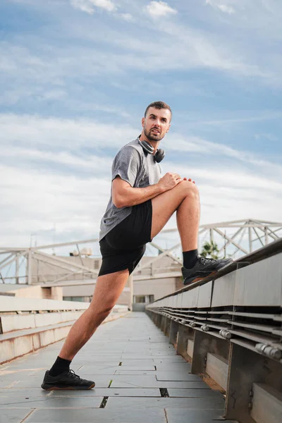垂直に カーディオランニングワークアウト後に脚を伸ばすアクティブスポーティな男 スポットマンは 健康的なライフスタイルを持つフィットネストレーニングルーチンで彼の筋肉を回復します 強さの練習をしている男 — ストック写真
