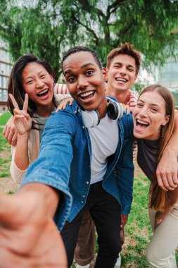 Neşeli arkadaşlarıyla gülen mutlu Afro-Amerikan gençliğinin dikey portresi. Bir grup çok ırklı genç öğrenci gülümseyip selfie çekiyorlar. Dostça buluşmada sınıf arkadaşları