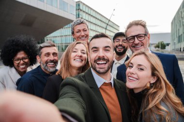 Bir grup iş adamı birlikte selfie çektirirken gülümsüyor. Bir sürü iş adamı kameraya bakıyor. Şirket kurma takımı eğleniyor. İyi giyimli yönetici şirket ortakların kutlu olsun. Yüksek