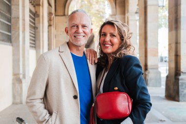 Yetişkin bir çiftin yatay portresi gülümseyen ve kameraya bakan. Orta yaşlı partnerler mutlu bir ifadeyle öne bakıyor. Orta yaşlı karı ve koca. Eş ve gri saçlı adam. Yüksek