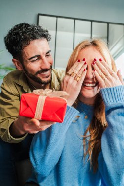 Dikey. Genç çift evlilik yıldönümlerini, doğum günlerini ya da sevgililer günlerini birlikte kutluyorlar. Mutlu karısı gözlerini kapatırken, sevgi dolu bir adam kurdeleyle romantik bir sürpriz hediye veriyor.