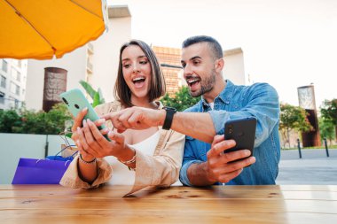 Mele ve kadın bir cep telefonuyla medyayı paylaşırken eğleniyorlar. Kahve dükkanının terasında akıllı telefon izleyen arkadaşlar. Şaşkın genç çift internetten alışveriş yapıyor. Cep telefonuyla satış buldukları için mutlular.