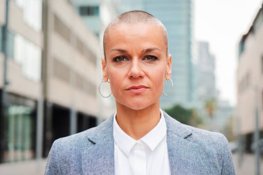 Kısa saçlı ciddi bir iş kadınının gururlu bir ifadeyle kameraya bakışının kişisel portresini kapat. Tezgahtar, ajan, avukat ya da yönetici işyerinin önüne bakıyor. Kendine güvenen bir kadın