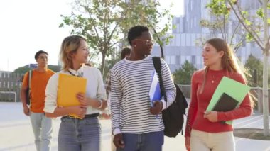 Üniversite kampüsünde birlikte yürüyen bir grup çok ırklı öğrenci. Sınıfa giderken gülen mutlu yurtiçi gençler. Genç arkadaşlar okula geri dönüyor. Dostça buluşmada sınıf arkadaşları. Yüksek