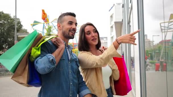 Alışveriş Torbaları Taşıyan Güzel Bir Kadın Mağaza Vitrinini Işaret Ediyor — Stok video