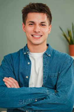 Genç, beyaz bir adamın dikey portresi gülümseyen ve kameraya dostça bir ifadeyle bakan. Beyaz dişli, gerçek bir genç öğrencinin resmi.