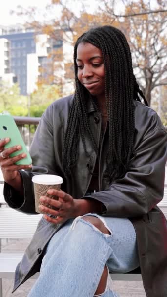 Dikey Gülümseyen Mutlu Afro Amerikalı Kız Dışarıda Bankta Cep Telefonuyla — Stok video