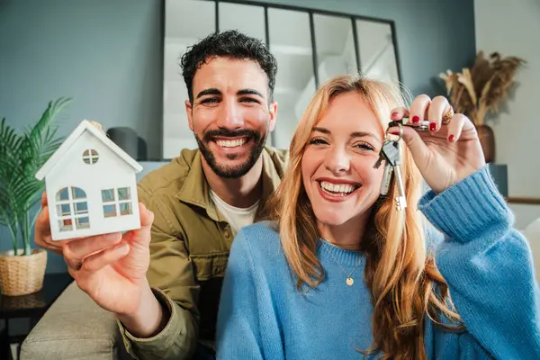 Evin anahtarını tutan genç çift yeni evlerinde bir başlangıç kutluyor. Emlak yatırımı. İpotek ya da kredi ilanı. Oturma odasında mutlu mülk sahipleri var. Evli insanların başarısı. Yüksek
