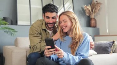 İnternetten alışveriş yapmak için cep telefonu kullanan beyaz bir çift gülümsüyor. Kadın ve erkek akıllı telefonuyla sosyal medyayı izliyor. Yetişkin arkadaşlar cep telefonlarıyla internette gezinirken eğleniyorlar