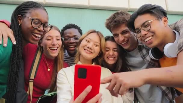 スマートフォンを使用して多民族の十代の友人の笑顔の大きなグループ 面白いビデオを見て オンラインでショッピング 屋外で楽しんでいます 携帯アプリで楽しいブラウジングをしている多民族の若者 — ストック動画