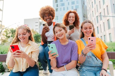Cep telefonlarını kullanarak eğlenen bir sürü kadın. Dışarıda oturan ve internette akıllı telefon bağlantısı uygulaması olan kadınlar var. Toplantıda cep telefonuyla sosyal medyayı izleyen kızlar